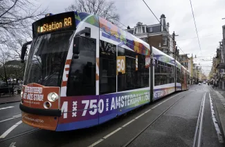 Amsterdamse tram met daarop kleurrijke tekst: 750 jaar Amsterdam